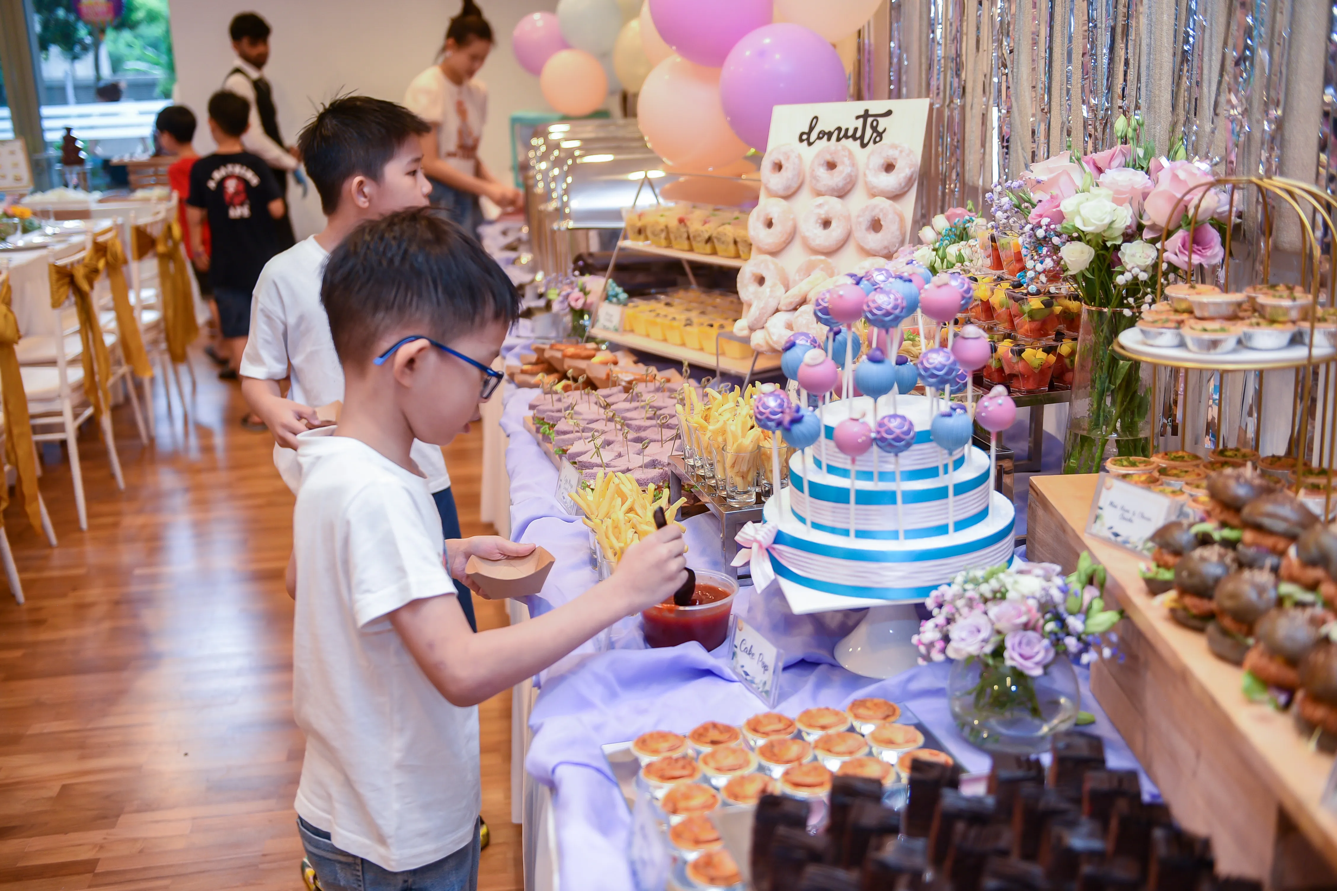 Kids birthday party dessert table with donuts, cake pops and balloon decor