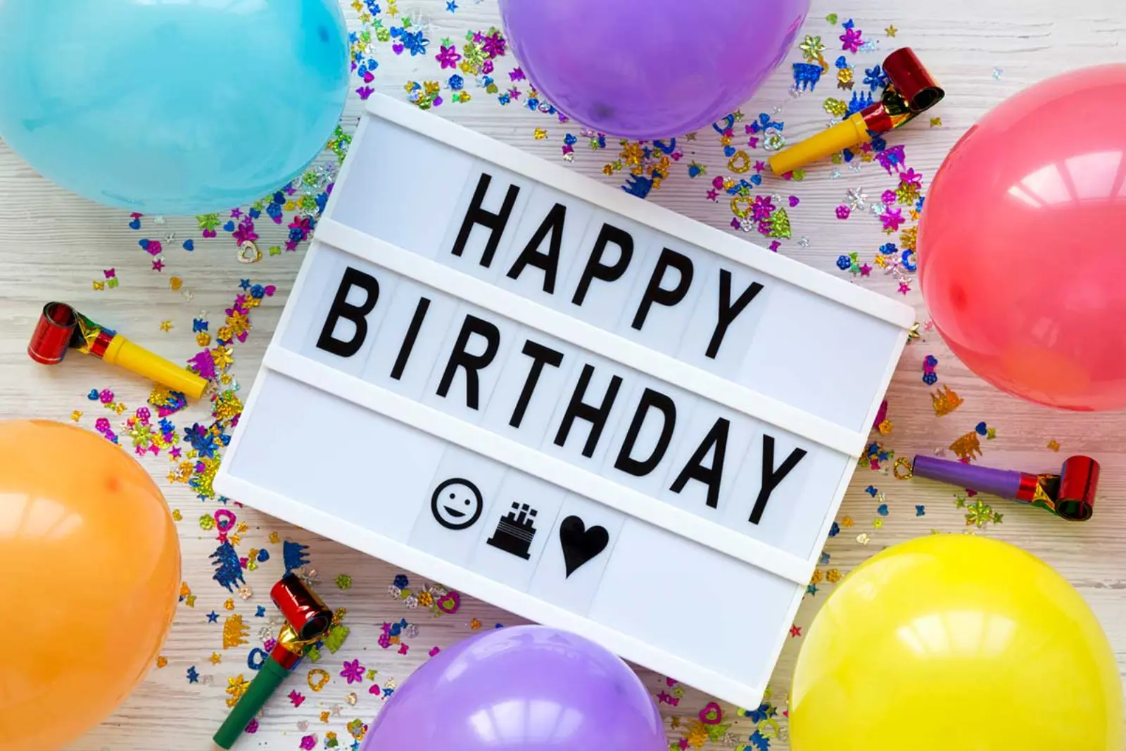 A happy birthday white board with balloons and birthday decorations