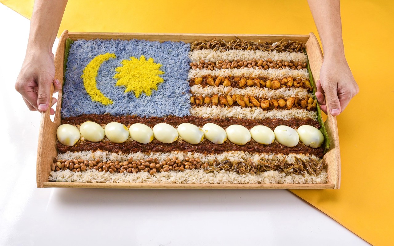 hand holding Malaysia's flag nasi lemak platter